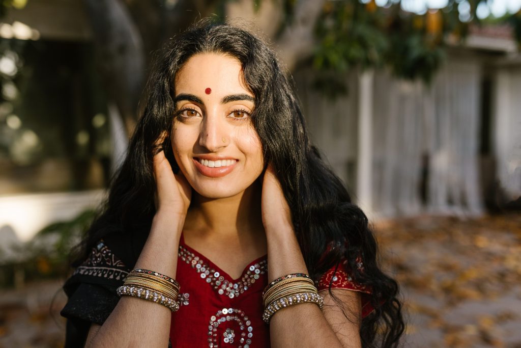 A woman in traditional Indian clothing with a vibrant smile and natural background.